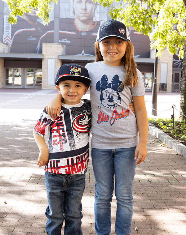 Two children smiling while wearing Columbus Blue Jacket gear