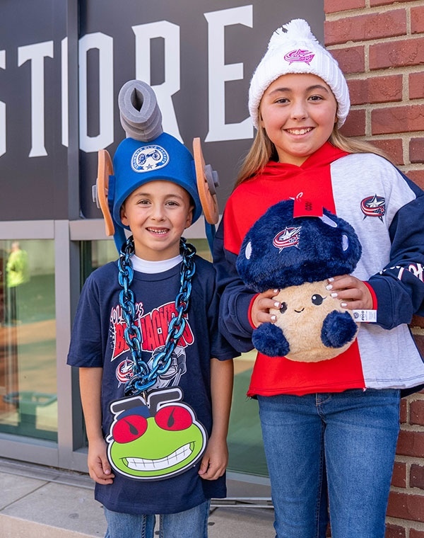Girl and boy wearing Columbus Blue Jacket shirt and holding novelty items