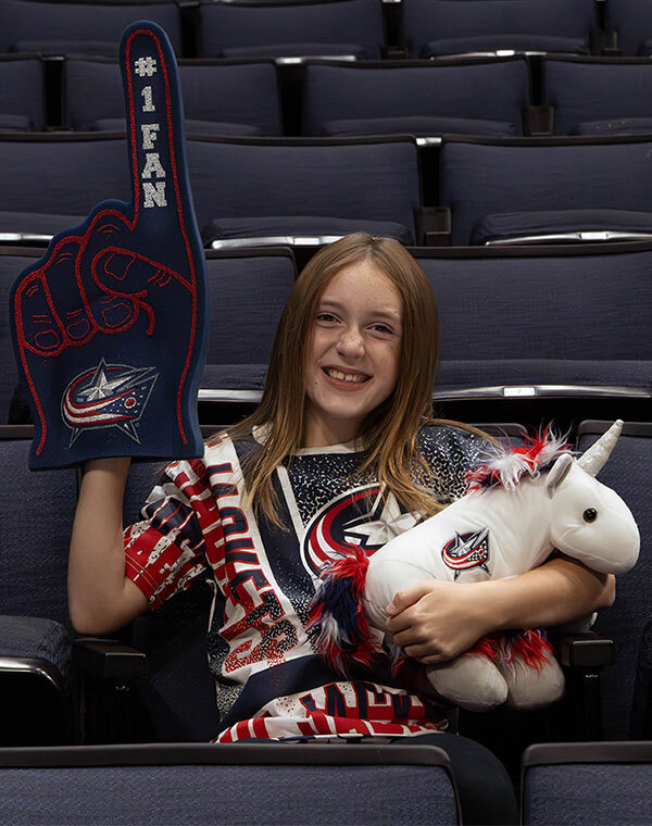 Girl wearing Columbus Blue Jacket shirt and holding novelty items